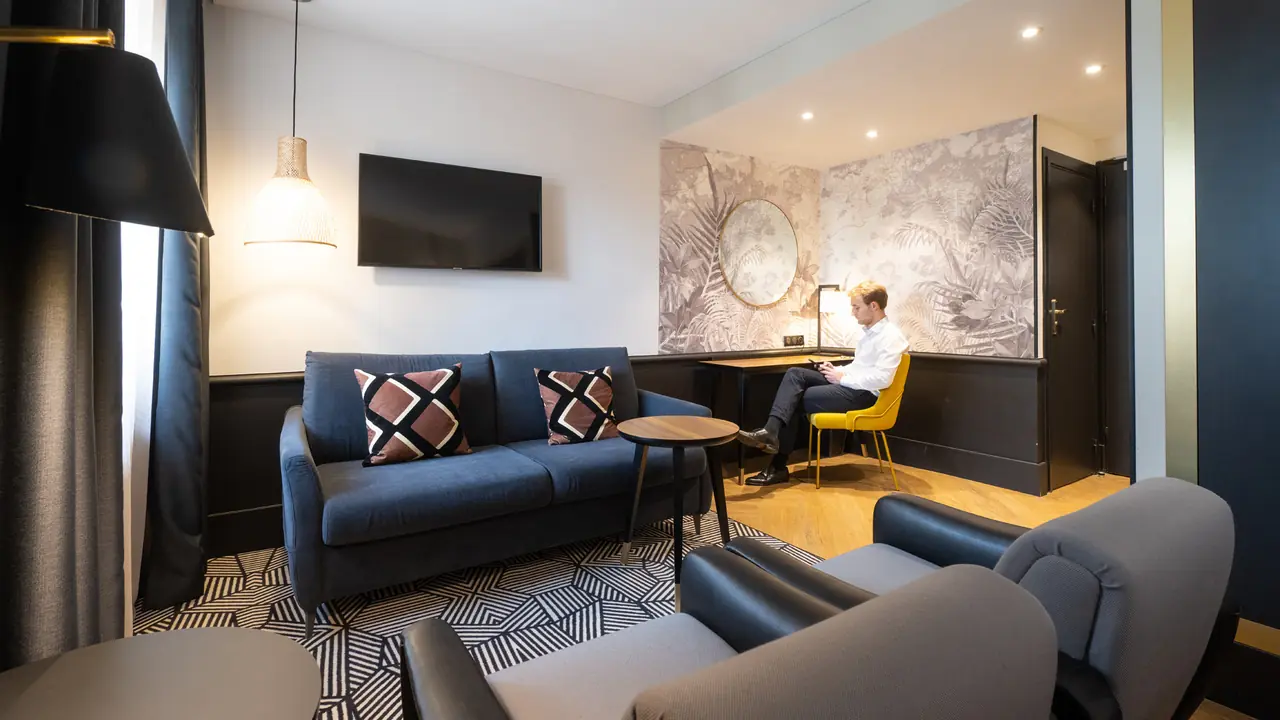 Salon d'une suite de l'Hôtel Roosevelt à Lyon, canapé bleu nuit et fresque murale, aménagé par Pépin de Banane